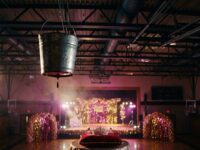 Cubeta metálica colgada sobre un gimnasio decorado para el baile de graduación, con una corona en primer plano