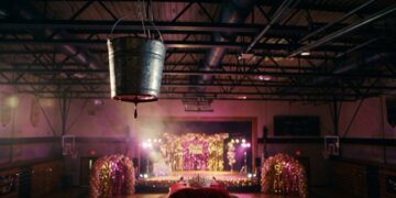 Cubeta metálica colgada sobre un gimnasio decorado para el baile de graduación, con una corona en primer plano
