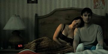 Una pareja en una habitación con papel tapiz antiguo y un reloj despertador, en una escena de terror romántico